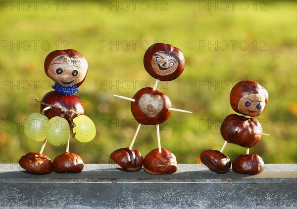 Three chestnut figures with grapes in the evening light