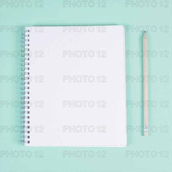 Blank spiral notebook with pencil turquoise background