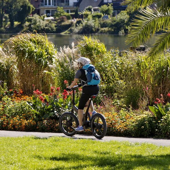 Bicycle rider on the Ruhr valley cycle path with lush vegetation at the reservoir