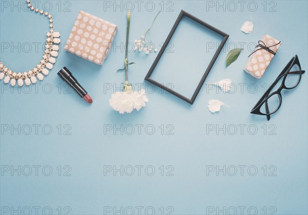 Blank frame with flowers gift boxes lipstick table