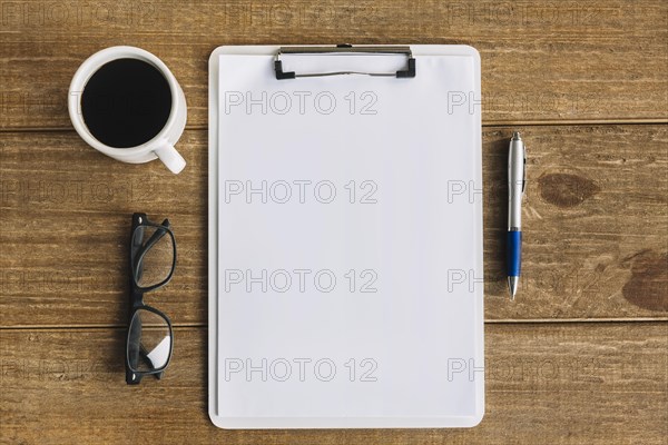 Black tea pen spectacles blank white papers with clipboard wooden background