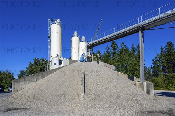 Steel silos and shovel crane with gravel piles and conveyor belt