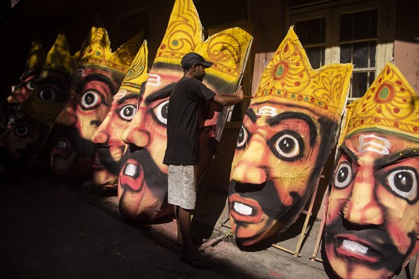 Artisan painting on a face of Ravana idol ahead of Dussehra Festival