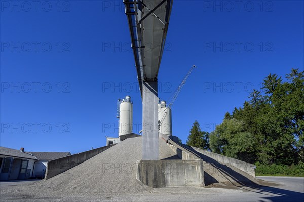 Steel silos and shovel crane with gravel piles and conveyor belt