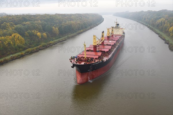 Cargo ship Chrysanthe sailing through the Kiel Canal in autumn and fog