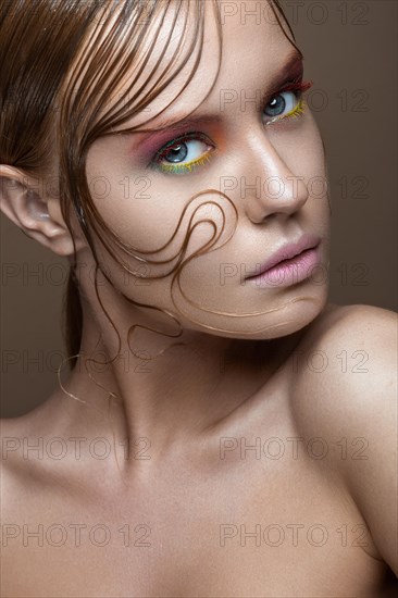 Beautiful girl with bright colored makeup and wet strands of hair on the face. Creative image. Picture taken in the studio