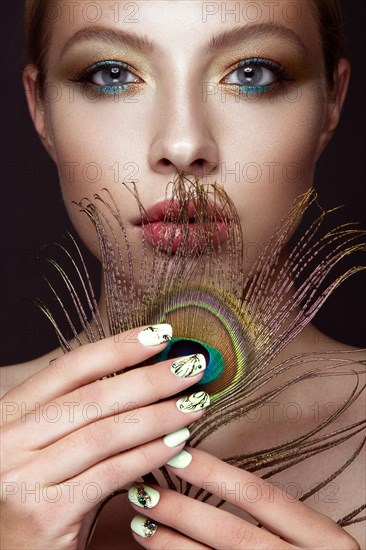 Beautiful girl with bright colored makeup and peacock feather on her face. Beauty face. Close-up. Photos shot in the studio