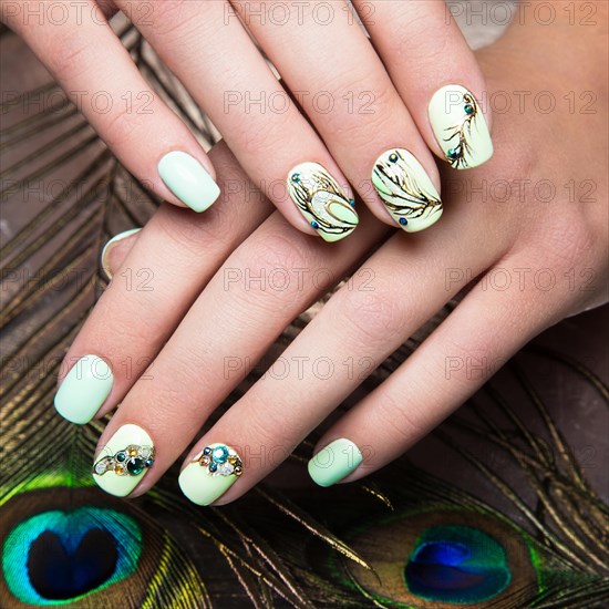 Art design manicure with peacock feather on female hands. Close-up. Fashion nails. Photos shot in studio