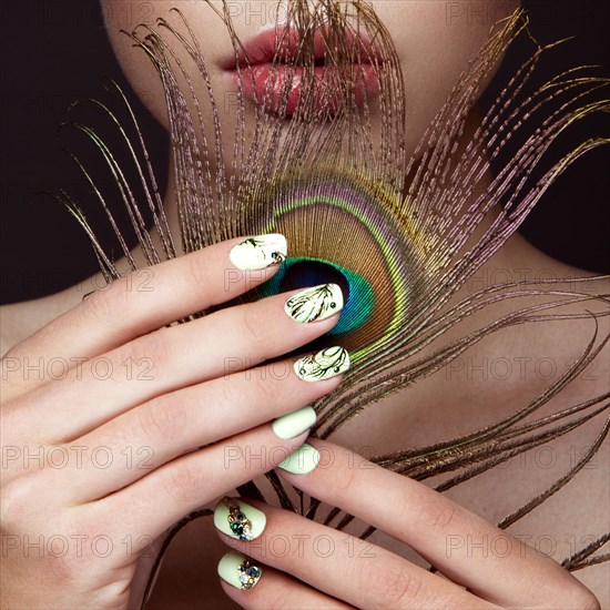 Beautiful girl with bright colored makeup and peacock feather on her face. Beauty face. Close-up. Photos shot in the studio