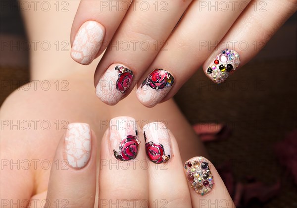 Beautiful manicure with flowers on female fingers. Nails design. Close-up. Picture taken in the studio on a white background