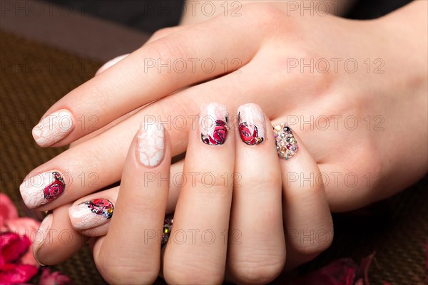 Beautiful manicure with flowers on female fingers. Nails design. Close-up. Picture taken in the studio on a white background