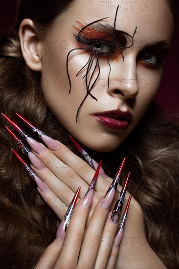 Portrait of woman in the image of spider with creative art makeup and long nails. Manicure design