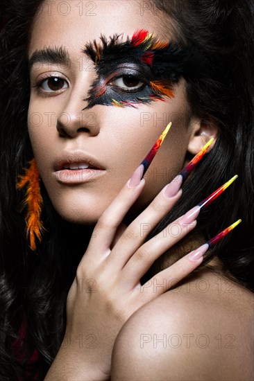 Beautiful girl in the image of the Phoenix bird with creative makeup and long nails. Manicure design. The beauty of the face. Photos shot in studio