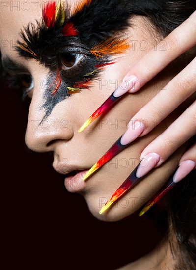 Beautiful girl in the image of the Phoenix bird with creative makeup and long nails. Manicure design. The beauty of the face. Photos shot in studio