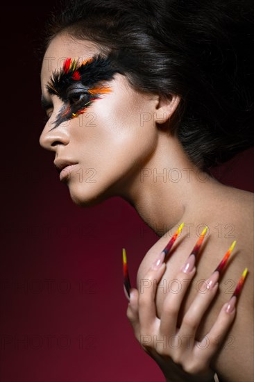 Beautiful girl in the image of the Phoenix bird with creative makeup and long nails. Manicure design. The beauty of the face. Photos shot in studio