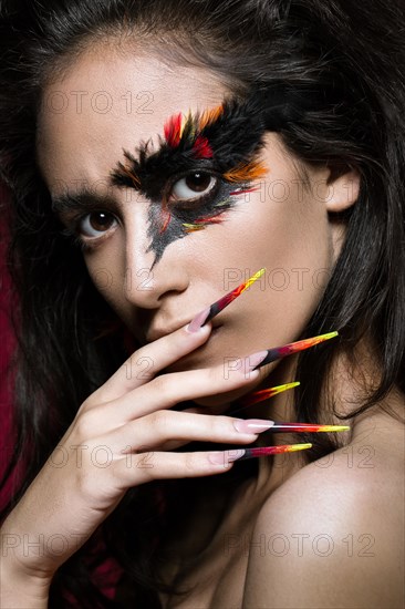 Beautiful girl in the image of the Phoenix bird with creative makeup and long nails. Manicure design. The beauty of the face. Photos shot in studio