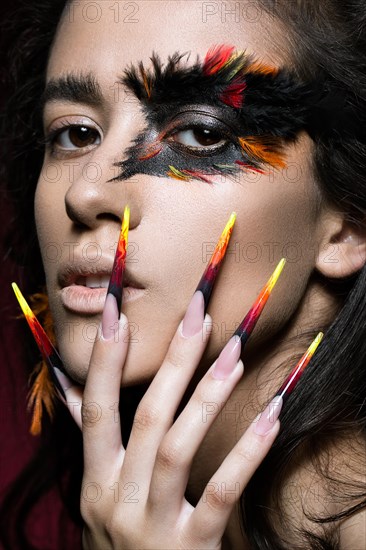 Beautiful girl in the image of the Phoenix bird with creative makeup and long nails. Manicure design. The beauty of the face. Photos shot in studio