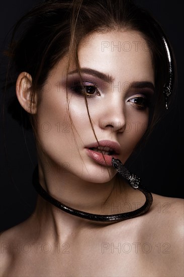 Beautiful girl with bright makeup and a fashionable hairdo with decoration in the form of a snake. The beauty of the face. Portrait shot in studio