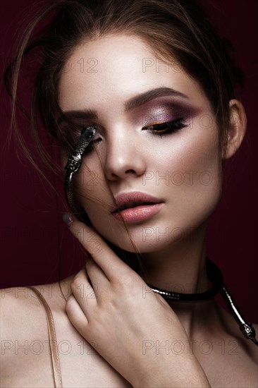 Beautiful girl with bright makeup and a fashionable hairdo with decoration in the form of a snake. The beauty of the face. Portrait shot in studio