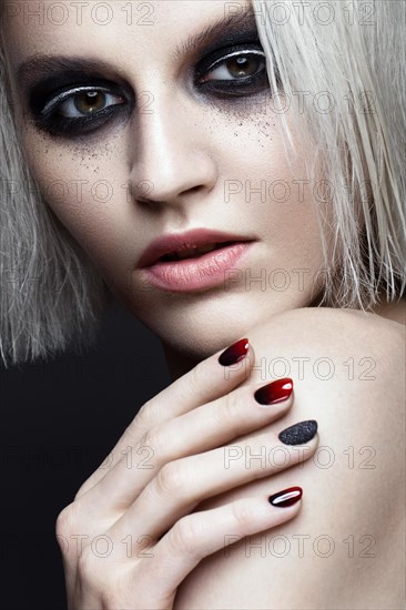 Beautiful blond girl with dark smokey makeup and art manicure design nails. beauty face. Photos shot in studio