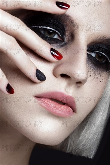 Beautiful blond girl with dark smokey makeup and art manicure design nails. beauty face. Photos shot in studio