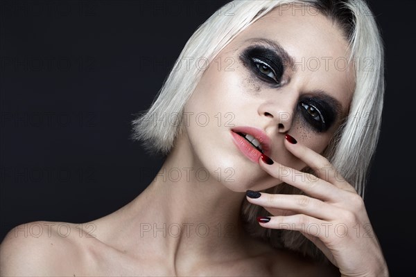 Beautiful blond girl with dark smokey makeup and art manicure design nails. beauty face. Photos shot in studio