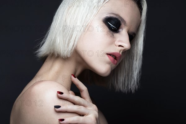 Beautiful blond girl with dark smokey makeup and art manicure design nails. beauty face. Photos shot in studio