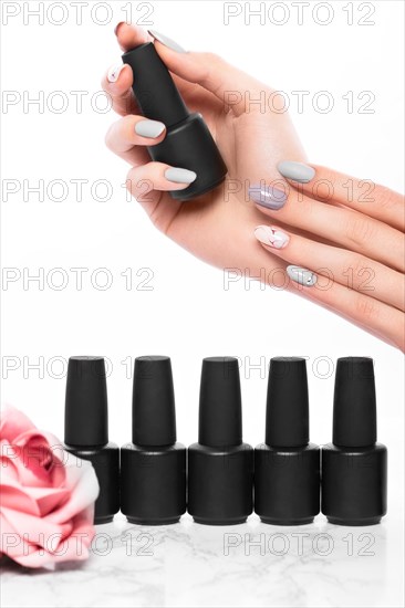 Black bottles of nail polish on a background of flowers. Manicure design