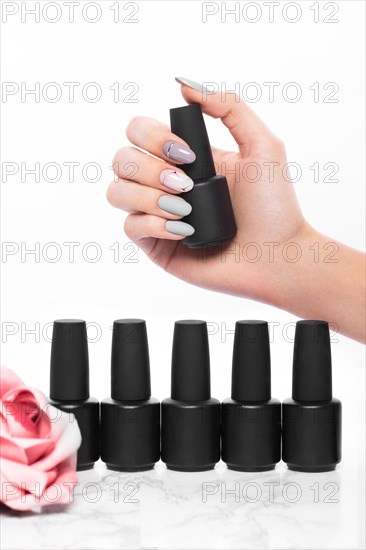 Black bottles of nail polish on a background of flowers. Manicure design