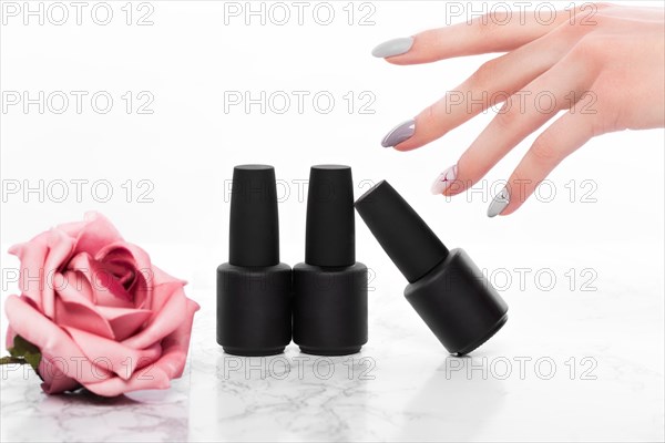 Black bottles of nail polish on a background of flowers. Manicure design