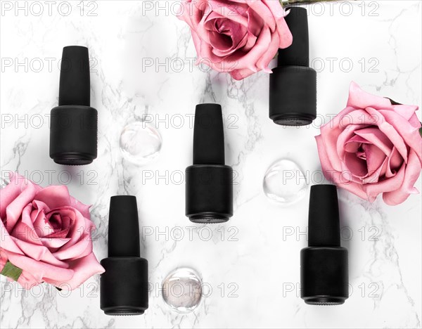 Black bottles of nail polish on a background of flowers. Manicure design