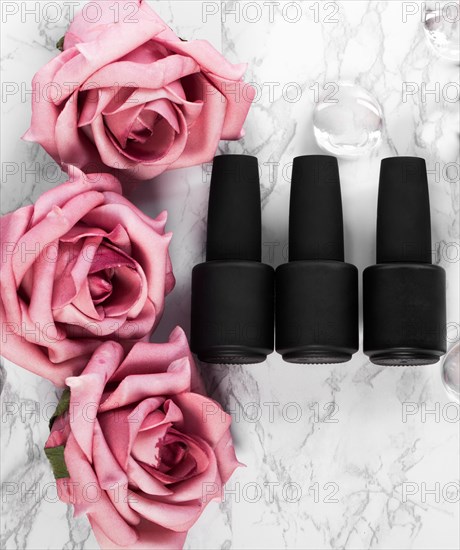 Black bottles of nail polish on a background of flowers. Manicure design