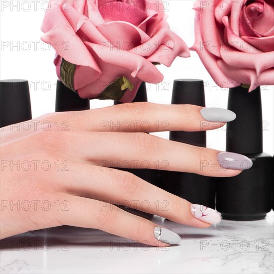 Black bottles of nail polish on a background of flowers. Manicure design