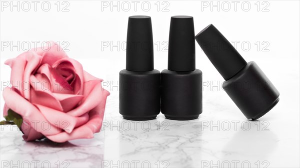 Black bottles of nail polish on a background of flowers. Manicure design