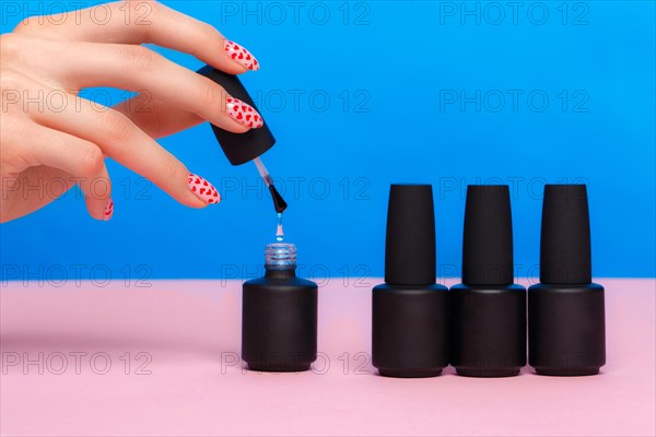 Black bottles of nail polish on a colorful background. Manicure design