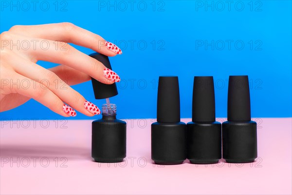 Black bottles of nail polish on a colorful background. Manicure design