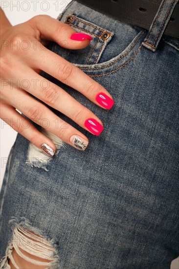 Bright neon manicure on female hands on the background of jeans. Nail design. Beauty hands