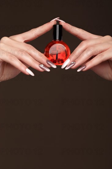 Beautiful classic manicure on female hand with oil for cuticles. Close-up. Picture taken in the studio
