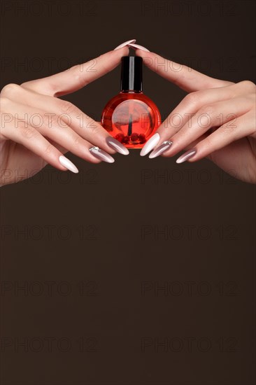 Beautiful classic manicure on female hand with oil for cuticles. Close-up. Picture taken in the studio