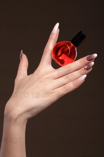 Beautiful classic manicure on female hand with oil for cuticles. Close-up. Picture taken in the studio