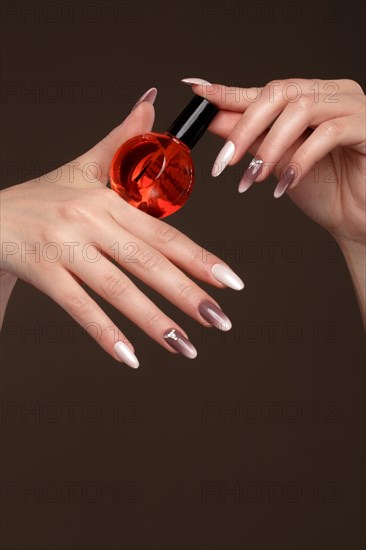 Beautiful classic manicure on female hand with oil for cuticles. Close-up. Picture taken in the studio