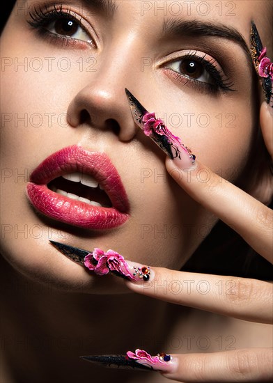 Beautiful girl with long nails and sensual lips. Portrait shot in the studio on a black background.Beauty face