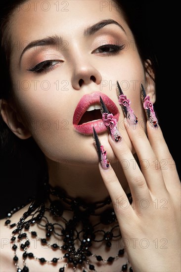 Beautiful girl with long nails and sensual lips. Portrait shot in the studio on a black background.Beauty face