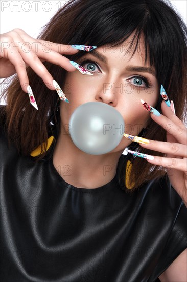 Photo of surprised woman in pop art style and design manicure with a bubble in the lips. Creative nails. Photos shot in studio