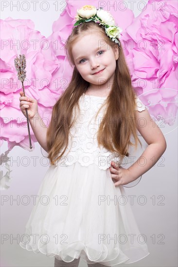 Little fairy girl in white dress on a background of flowers. Photo taken in studio