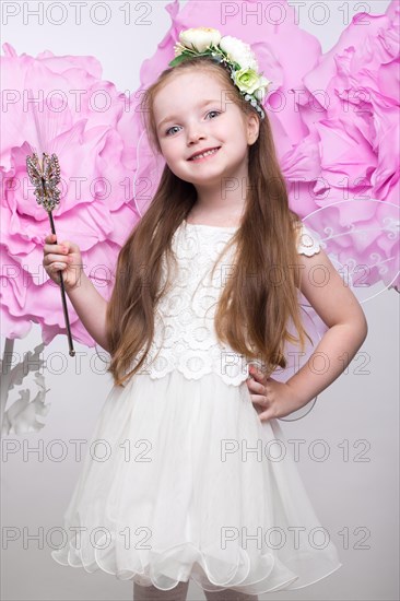 Little fairy girl in white dress on a background of flowers. Photo taken in studio