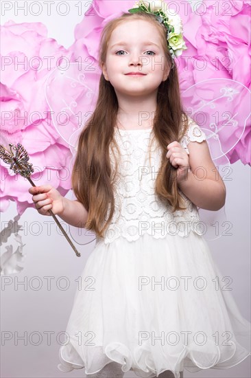 Little fairy girl in white dress on a background of flowers. Photo taken in studio