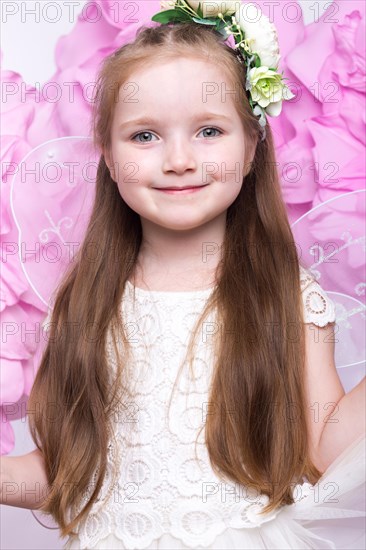 Little fairy girl in white dress on a background of flowers. Photo taken in studio