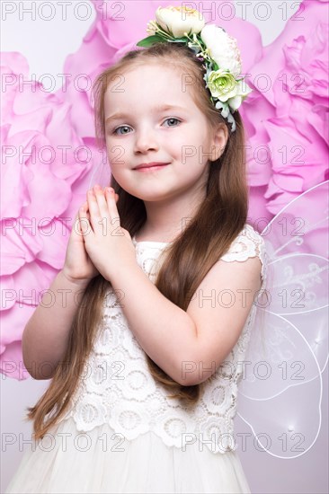 Little fairy girl in white dress on a background of flowers. Photo taken in studio