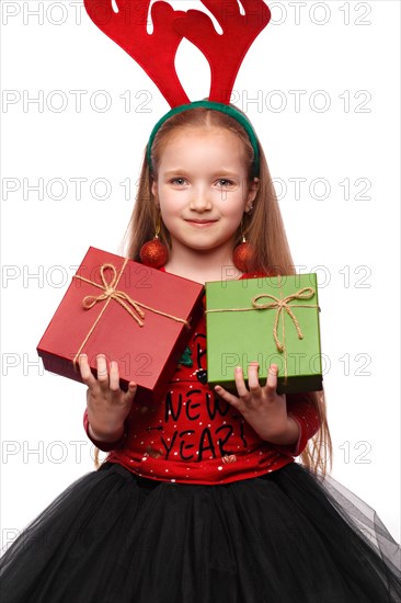 Beautiful little girl in a New Year's image with boxes of gifts in hands and deer horns on her head. Photo taken in the studio